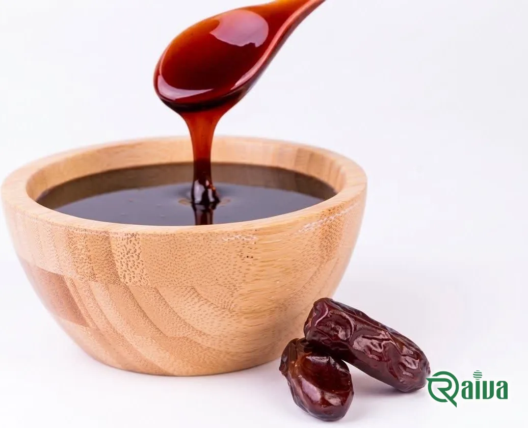 Dark date syrup running from a spoon into a wooden bowl