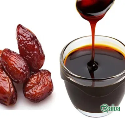 Dark date syrup running from a spoon into a wooden bowl (view 3)
