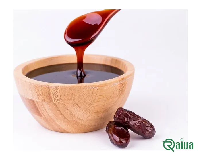 Dark date syrup running from a spoon into a wooden bowl