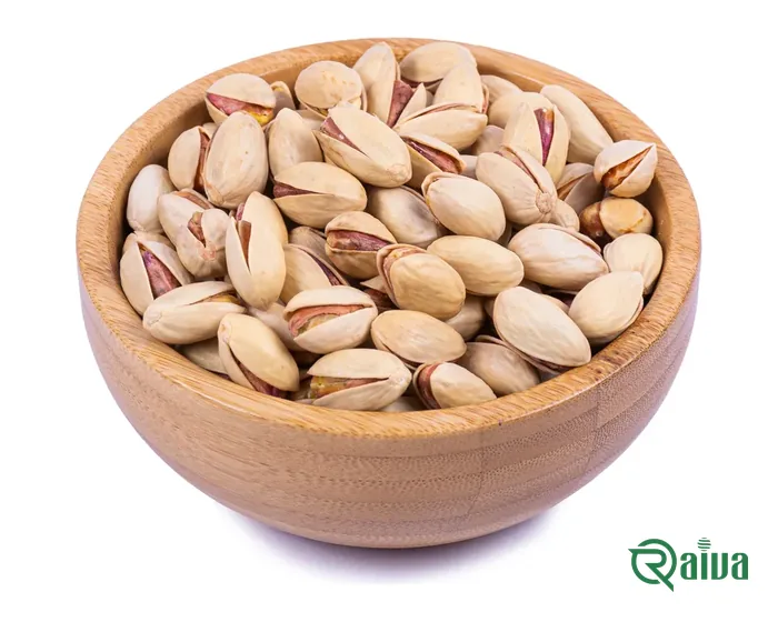 In-shell pistachios heaped in a wooden bowl, split shells showing