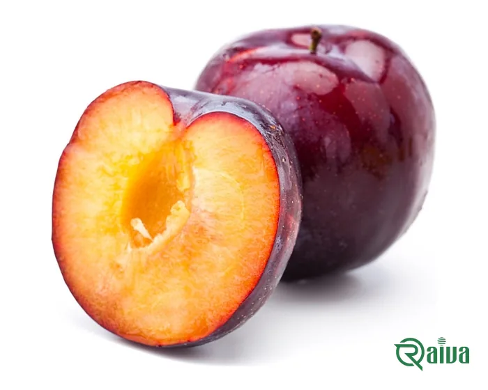 A dark plum cut open to show amber flesh, beside whole plums