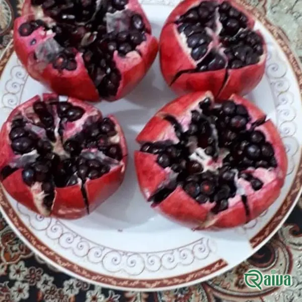 Two whole red pomegranates beside a broken piece full of dark red arils (view 18)