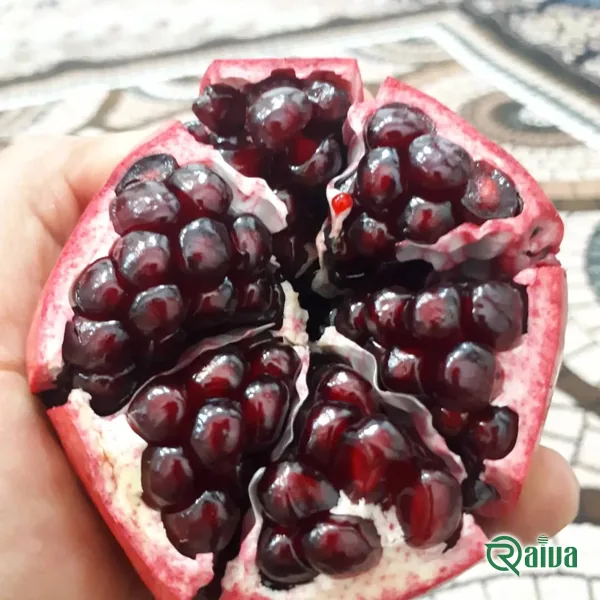 Two whole red pomegranates beside a broken piece full of dark red arils (view 19)
