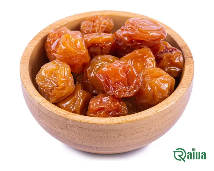 Dried plums with a soft amber skin in a wooden bowl