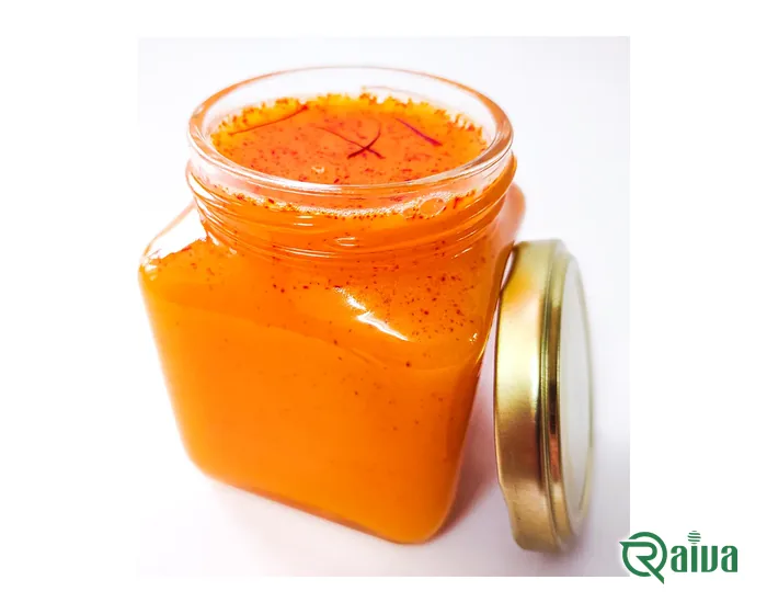 An open glass jar of orange saffron honey flecked with saffron, its lid beside it